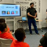 Kids watching presenter, screen says URI AI Lab